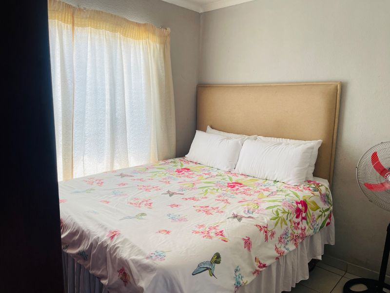 A functional bedroom featuring tiled flooring and natural light from the window, providing a comfortable space for rest.