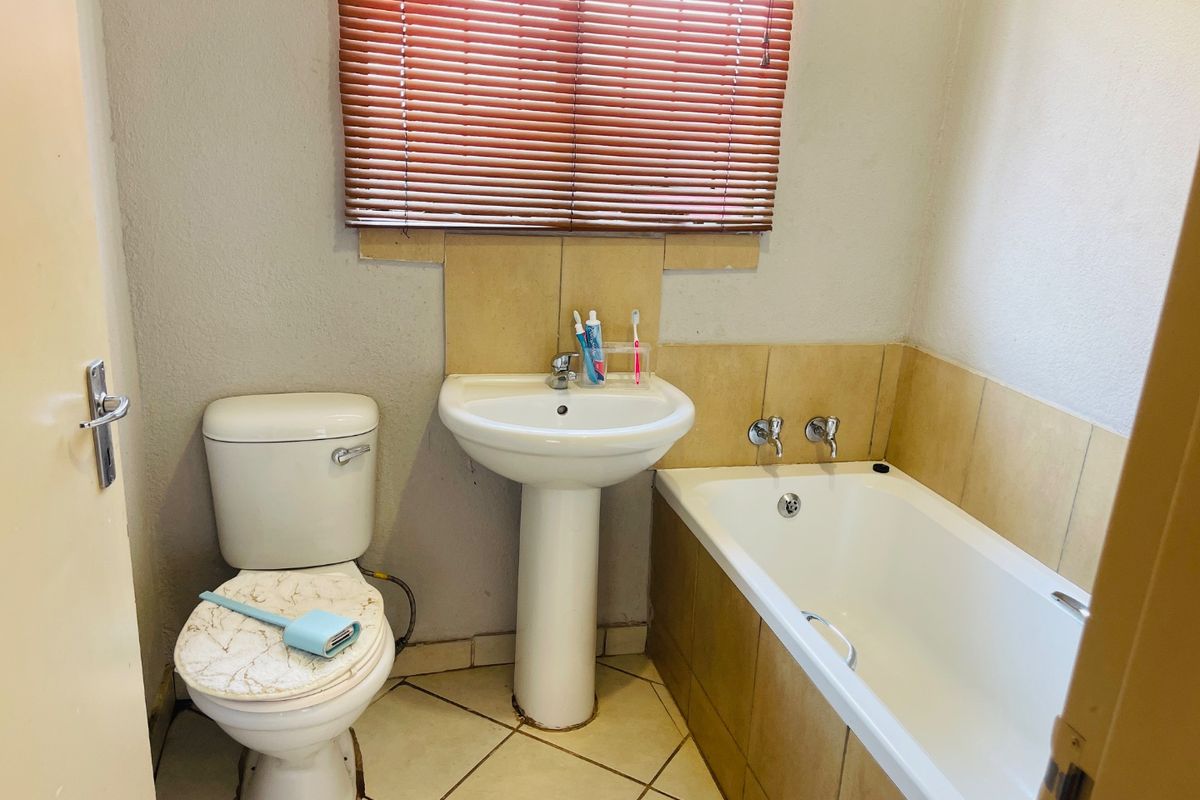 A compact bathroom featuring a pedestal basin, standard toilet, and bathtub with tiled splashbacks and neutral flooring.
