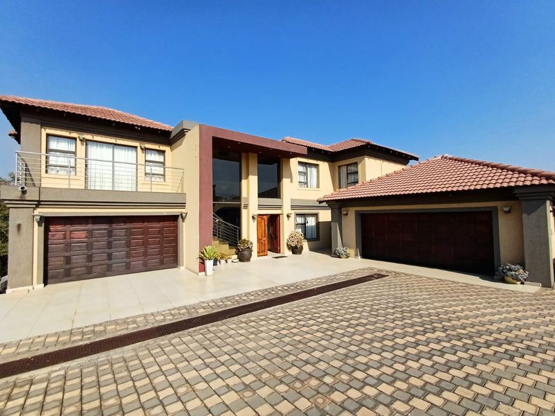 A modern double-storey residence featuring a paved driveway, two double garages, and a prominent double-volume entrance with a balcony.