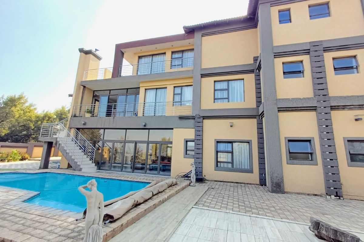 Rear elevation of a multi-story house featuring a swimming pool, paved patio area, multiple balconies, and large glass sliding doors.