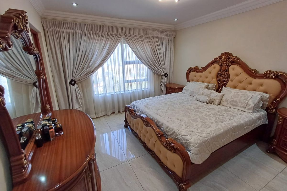 A well-maintained bedroom featuring polished tiled flooring, recessed ceiling lighting, and decorative cove cornicing, providing a clean and comfortable living space.