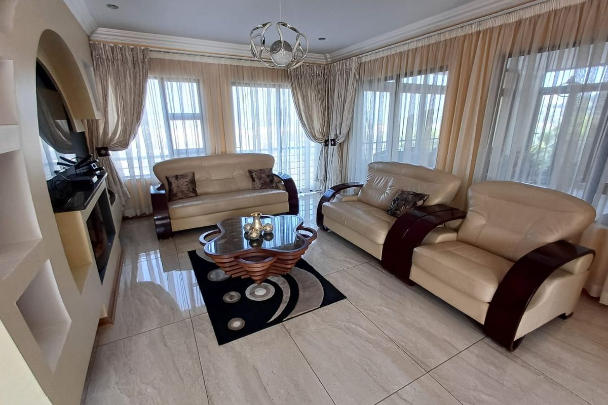 Spacious living room featuring large windows with natural light, tiled flooring, a built-in fireplace, and recessed wall shelving.