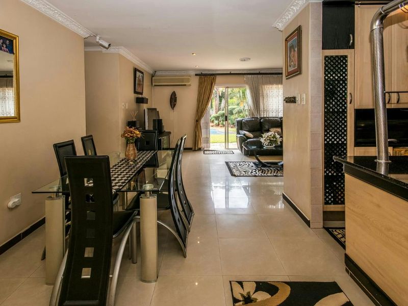 Open-plan living and dining area featuring tiled floors, crown molding, and direct access to the outdoor patio through sliding glass doors.