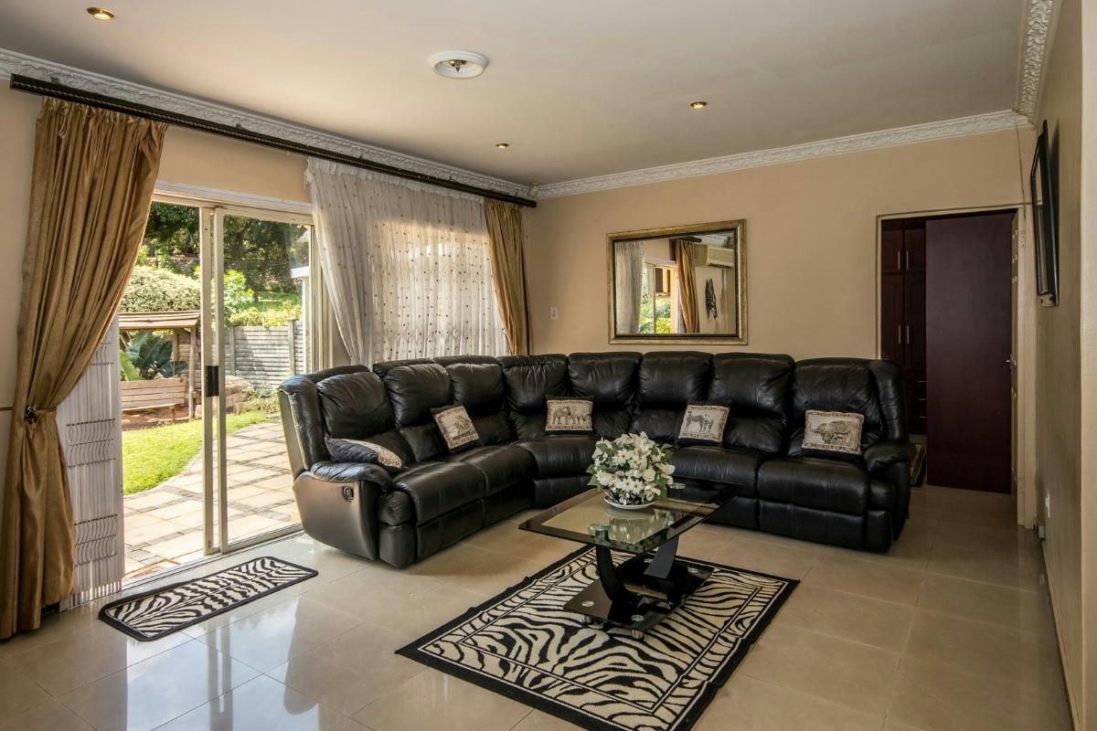 Spacious living room featuring tiled floors, crown molding, and a large sliding glass door providing direct access to the outdoor patio and garden area.