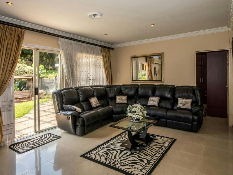 Spacious living room featuring tiled floors, crown molding, and a large sliding glass door providing direct access to the outdoor patio and garden area.