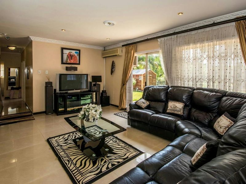Spacious living room featuring tiled flooring, recessed lighting, decorative crown molding, and a sliding glass door providing access to the garden.
