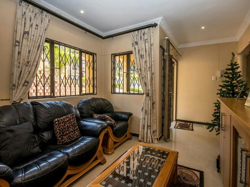 A comfortable living room featuring tiled flooring, decorative cornicing, and security bars on the windows, providing a functional and secure living space.
