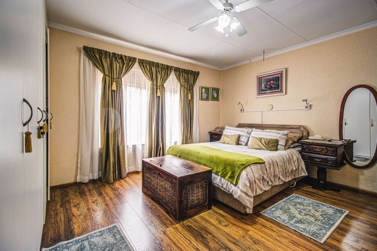 A well-maintained bedroom featuring laminate flooring, a ceiling fan, and built-in wardrobe storage with neutral wall finishes.