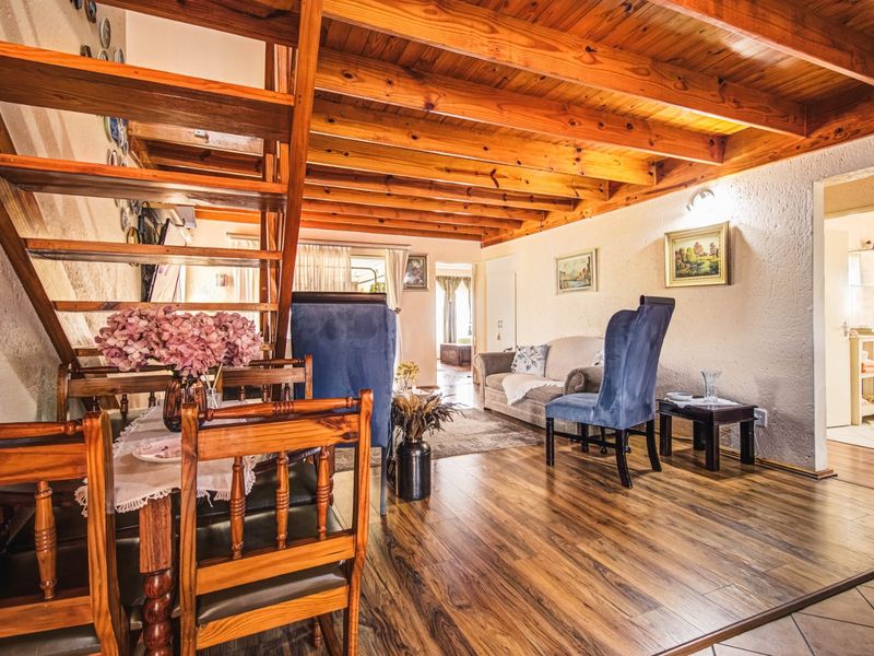 Open plan living area featuring exposed timber ceiling beams, a wooden staircase, and laminate flooring, creating a warm and rustic atmosphere.