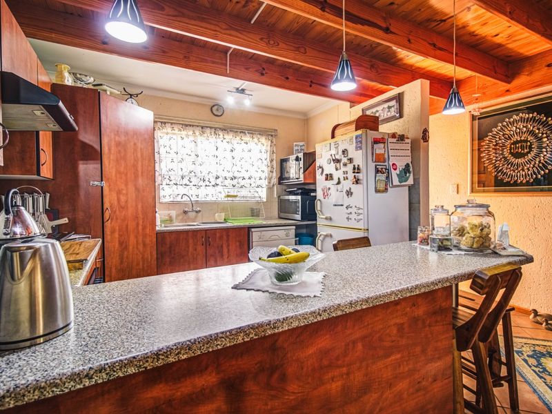 A functional kitchen featuring warm wooden cabinetry, granite countertops, and exposed timber ceiling beams, creating a rustic and inviting culinary space.