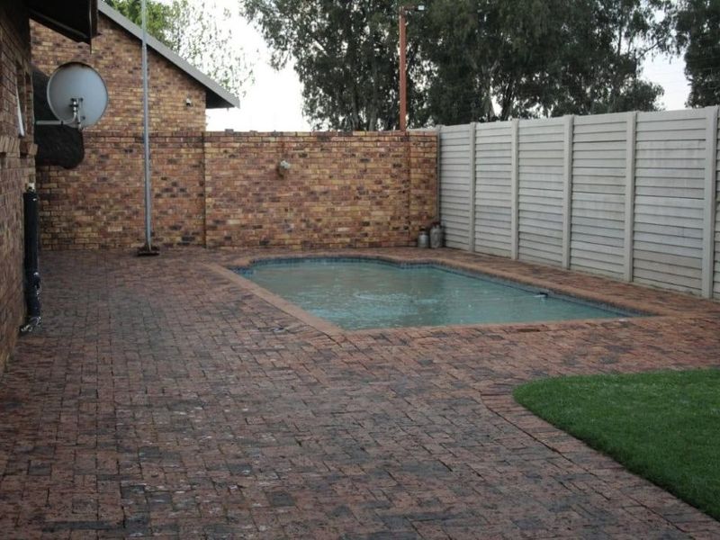 Outdoor pool area featuring brick paving, a swimming pool, and a combination of brick and precast concrete boundary walls.