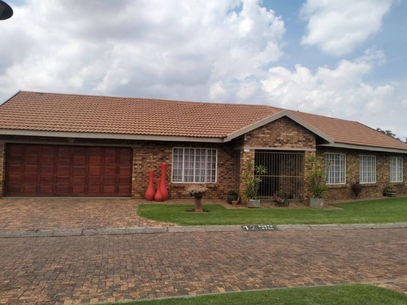 Front elevation of a single-story brick house featuring a tiled roof, paved driveway, and an integrated double garage.
