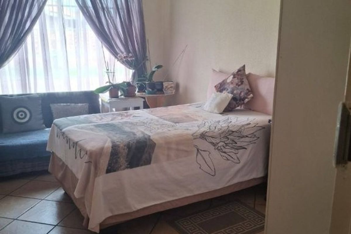A functional bedroom featuring tiled flooring and a built-in cupboard, offering a neutral space ready for personalization.