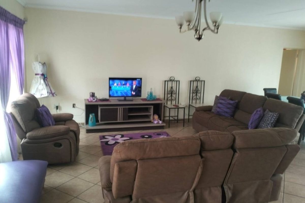 A spacious living room featuring tiled flooring and a central chandelier, providing a comfortable and functional area for relaxation.