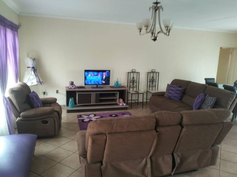 A spacious living room featuring tiled flooring and a central chandelier, providing a comfortable and functional area for relaxation.