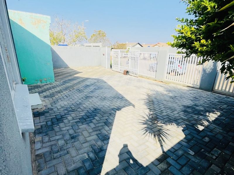 A paved rear courtyard area featuring a boundary wall and metal gate access, providing a functional outdoor space.