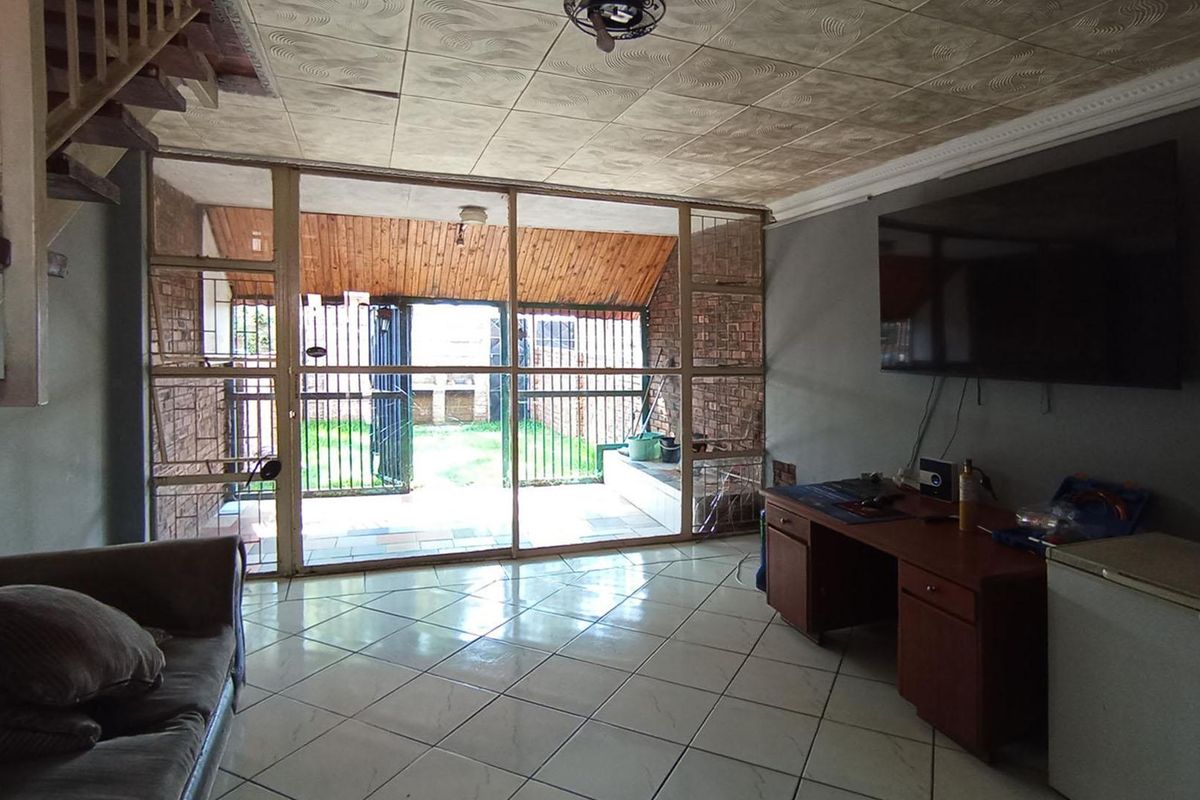Living room featuring tiled flooring, a staircase, and large sliding glass doors providing access to the rear patio area.