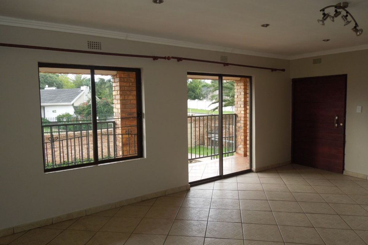Spacious living area featuring neutral tiled flooring, recessed lighting, and large sliding glass doors providing access to an outdoor patio area.