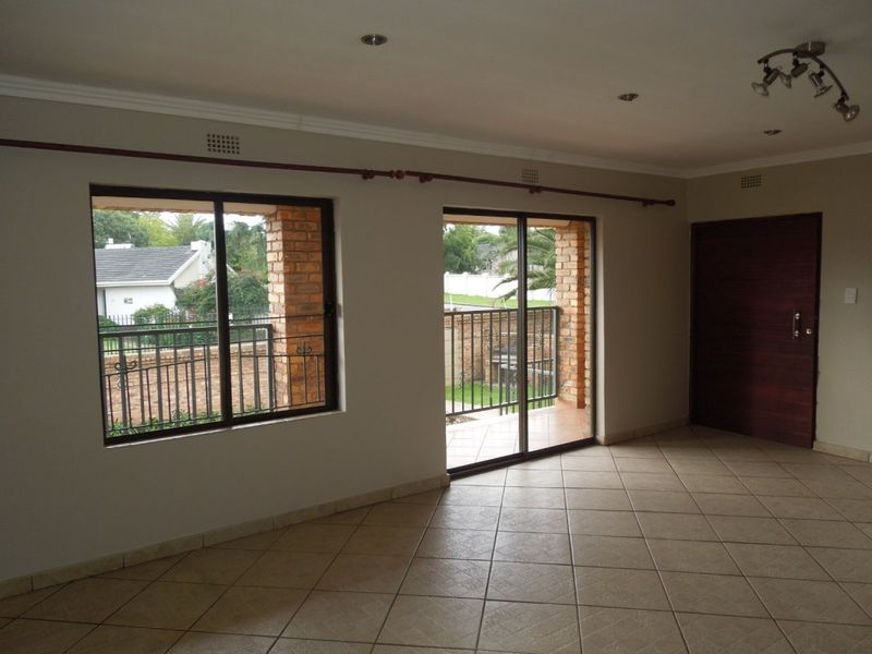 Spacious living area featuring neutral tiled flooring, recessed lighting, and large sliding glass doors providing access to an outdoor patio area.