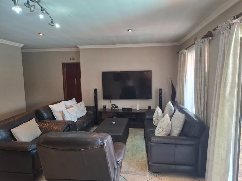 A comfortable living room featuring tiled flooring, crown molding, and recessed lighting, providing a functional space for relaxation and entertainment.