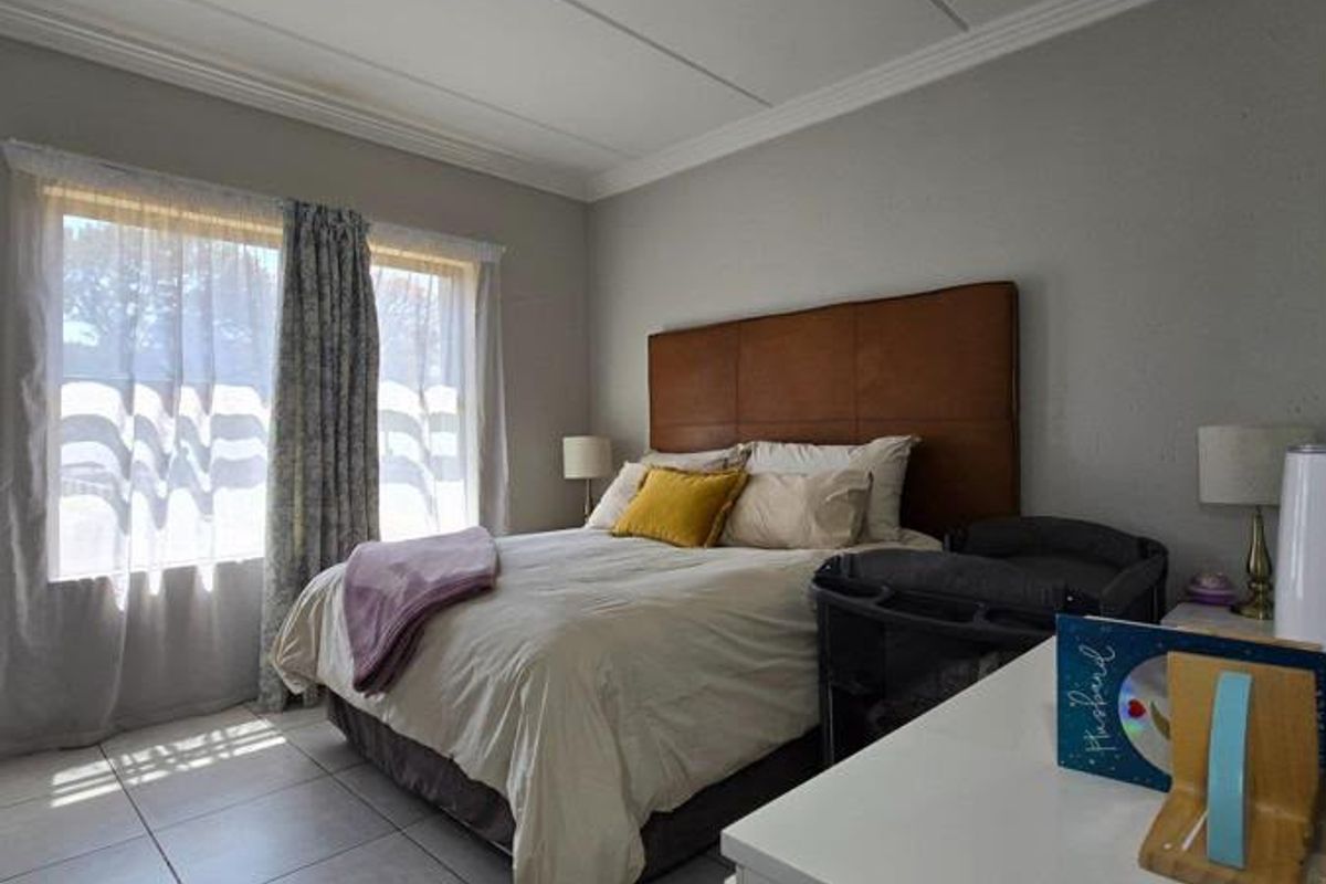 A well-lit bedroom featuring tiled flooring, crown molding, and a large window allowing for natural light.