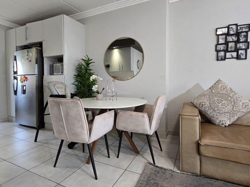 An open-plan living and dining area featuring neutral tiled flooring, built-in cabinetry, and coved ceiling details.