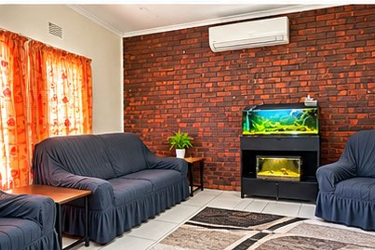 A living room featuring an exposed brick accent wall, tiled flooring, and a wall-mounted air conditioning unit.