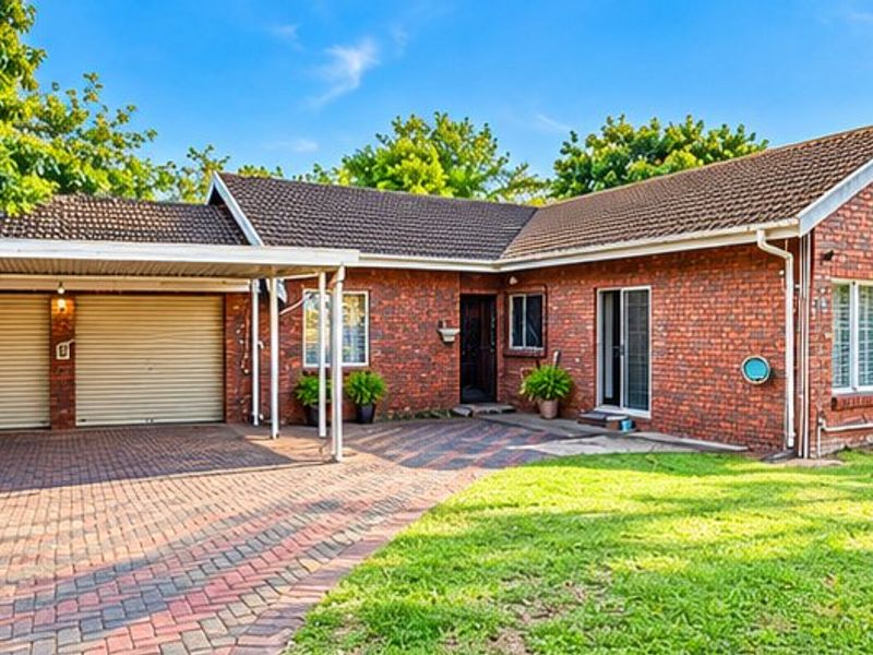 A well-maintained single-story brick house featuring a double garage, attached carport, paved driveway, and a neat front lawn.