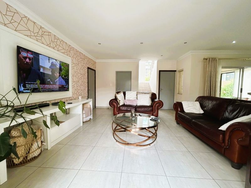 Spacious living room featuring large format floor tiles, recessed downlighting, and a modern decorative feature wall with a built-in media console.