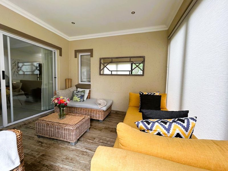 A bright, enclosed patio area featuring tiled flooring, recessed lighting, and large sliding glass doors providing seamless access to the interior living space.