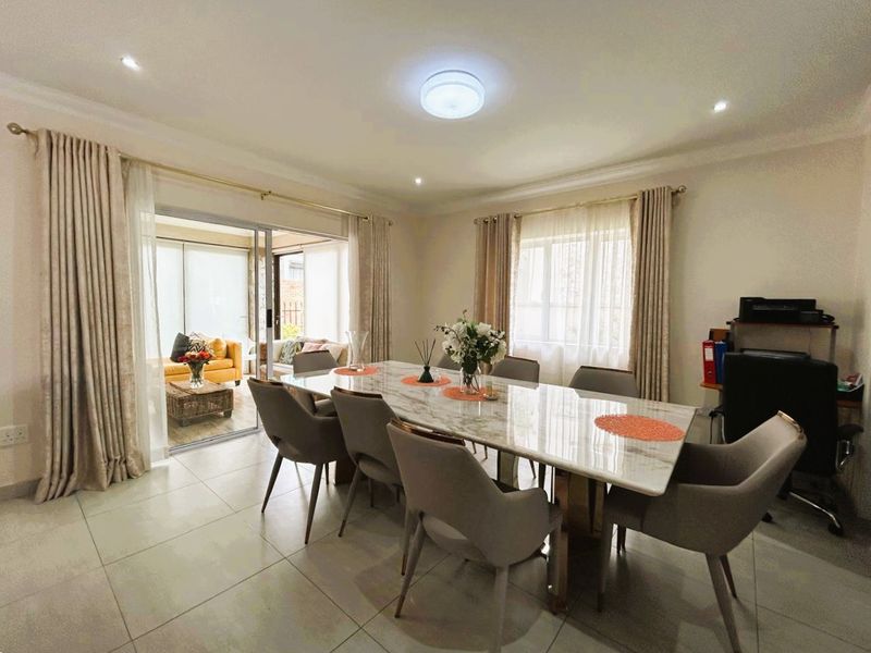 A bright and spacious dining area featuring large format floor tiles, recessed lighting, and sliding glass doors providing seamless access to the outdoor patio.