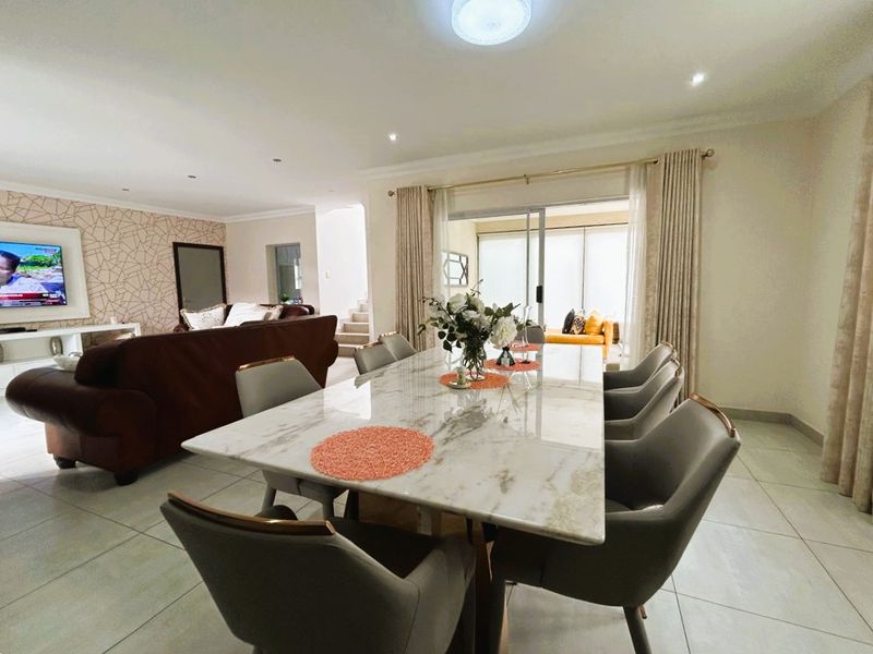 Spacious open-plan living and dining area featuring tiled flooring, recessed lighting, and large sliding glass doors providing access to the patio.