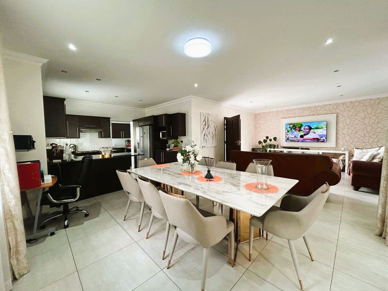 Spacious open-plan living area featuring a modern kitchen with dark cabinetry, a dining space, and a lounge area with feature wallpaper.