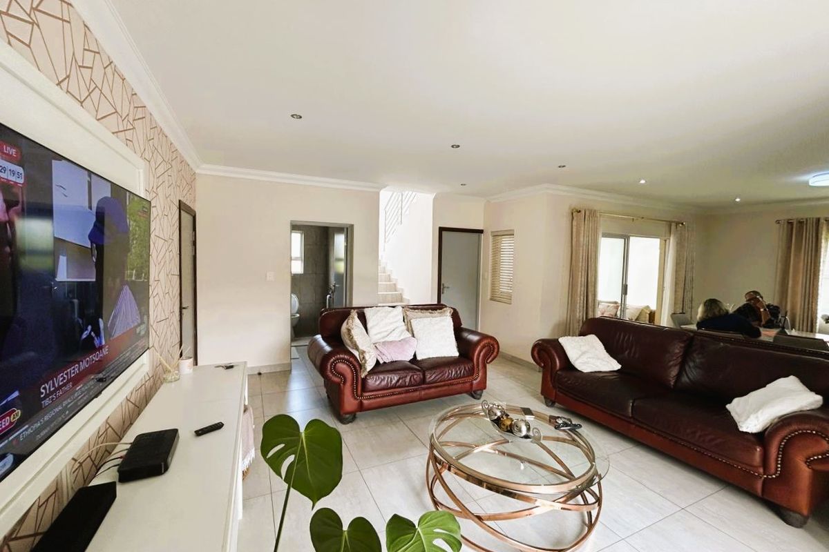 Spacious open-plan living area featuring tiled flooring, recessed downlighting, and sliding glass doors providing natural light and access to the exterior.