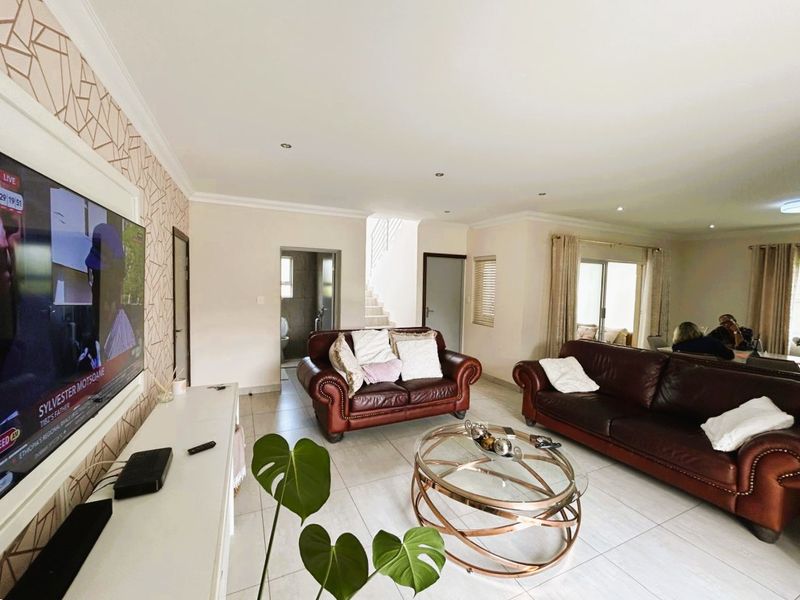 Spacious open-plan living area featuring tiled flooring, recessed downlighting, and sliding glass doors providing natural light and access to the exterior.