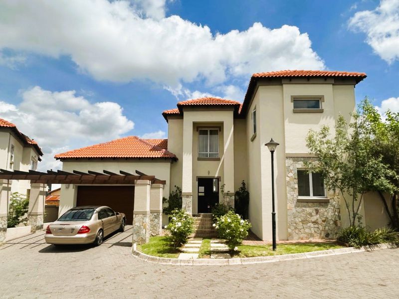 Front elevation of a double-story townhouse featuring terracotta roof tiles, stone cladding accents, a wooden pergola over the driveway, and a paved entrance path.