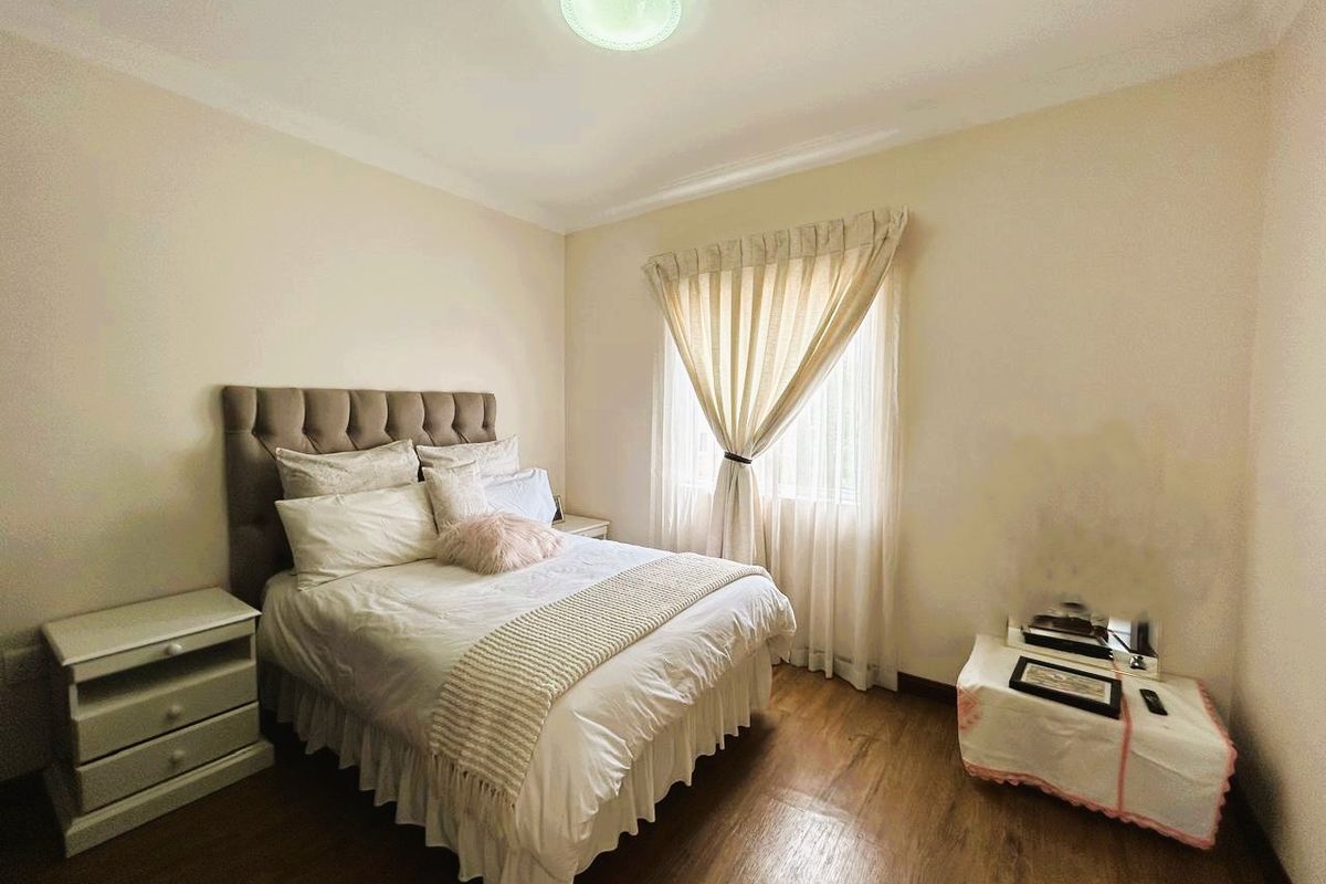 A well-maintained bedroom featuring laminate flooring, coved cornicing, and a central ceiling light fixture.