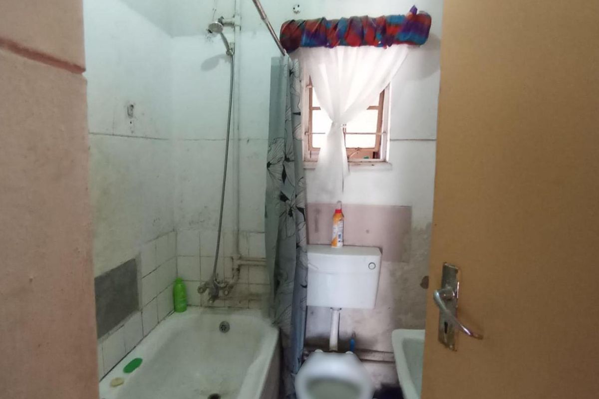 A compact bathroom featuring a bathtub, toilet, and washbasin, currently requiring significant renovation and cosmetic updates to improve its overall condition and appeal.