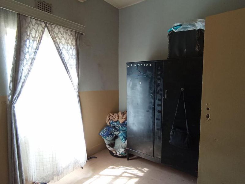 A bedroom featuring a window and built-in storage, currently showing signs of wear and requiring cosmetic updates to improve its overall condition.