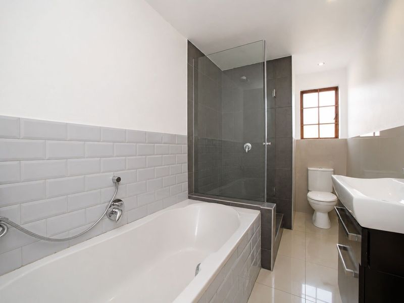 Modern bathroom featuring a built-in bathtub, separate glass-enclosed shower, subway tile detailing, and a contemporary vanity basin.