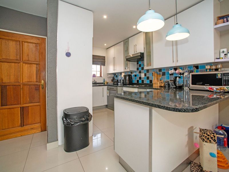 A functional kitchen featuring granite countertops, white cabinetry, a mosaic tile backsplash, and tiled flooring, offering a practical layout for daily meal preparation.