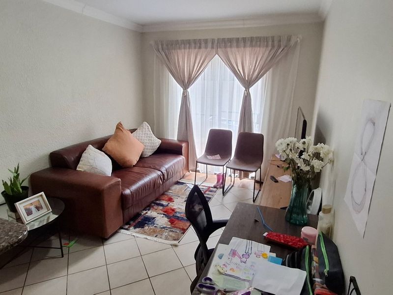 An open-plan living area featuring tiled flooring, coved ceilings, and a sliding glass door providing natural light.