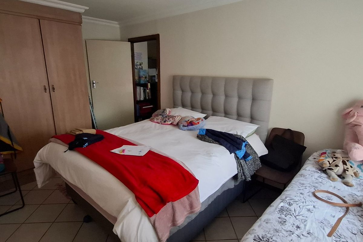 A functional bedroom featuring tiled flooring, a built-in wardrobe, and decorative coving, providing a practical living space.