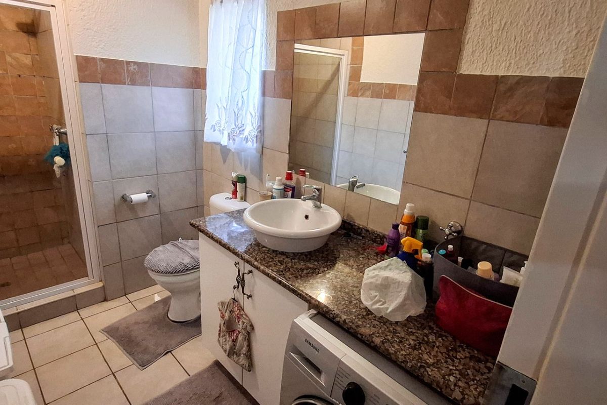 A functional bathroom featuring a shower enclosure, granite-topped vanity with a vessel sink, and tiled finishes throughout.