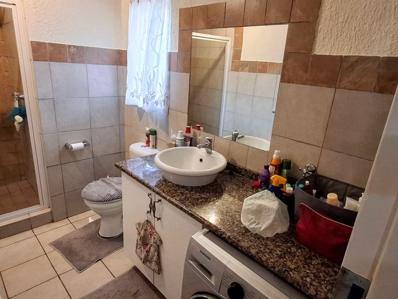 A functional bathroom featuring a shower enclosure, granite-topped vanity with a vessel sink, and tiled finishes throughout.