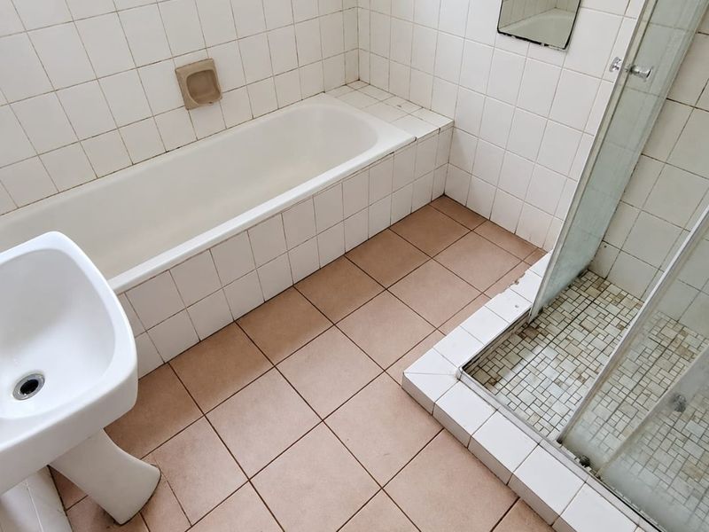 A dated bathroom featuring a built-in bathtub, separate shower enclosure, and pedestal basin, finished with ceramic wall and floor tiles.