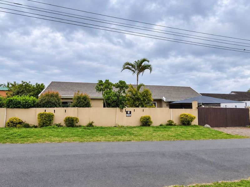 Front view of a single-story residential property featuring a perimeter boundary wall, tiled roof, and gated driveway access.
