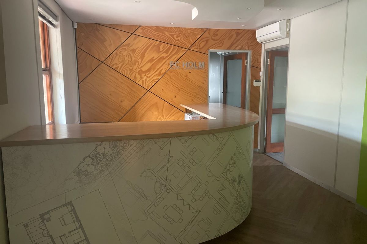 A professional commercial reception area featuring a custom curved desk, timber feature wall, and modern recessed ceiling lighting.