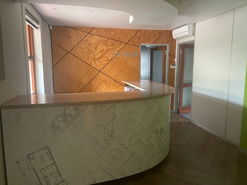 A professional commercial reception area featuring a custom curved desk, timber feature wall, and modern recessed ceiling lighting.