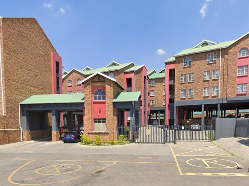 Front elevation of Grand Central Apartments featuring a brick facade, covered entrance portico, and secure gated access.
